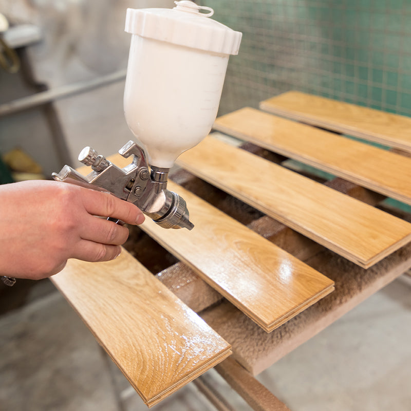 spraying America's Best Solvent-Based Varnish onto wooden panels with spray gun